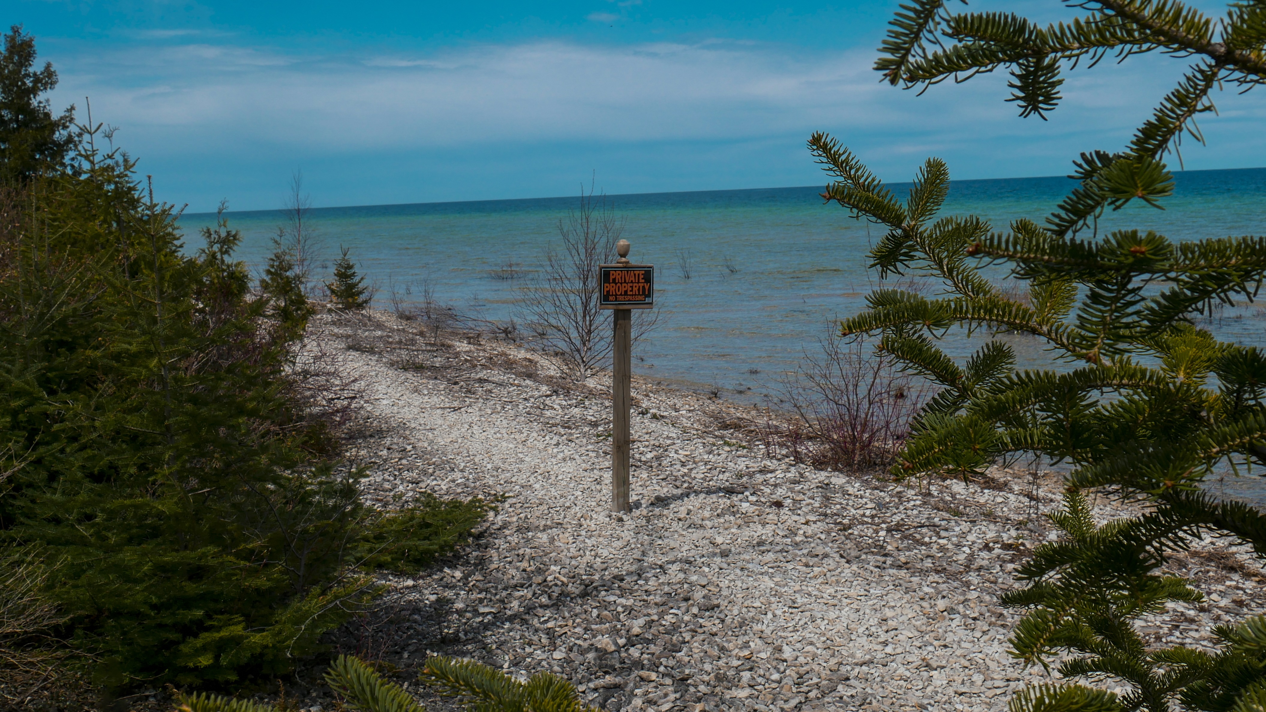 Rocky beach with private property sign and evergreen trees